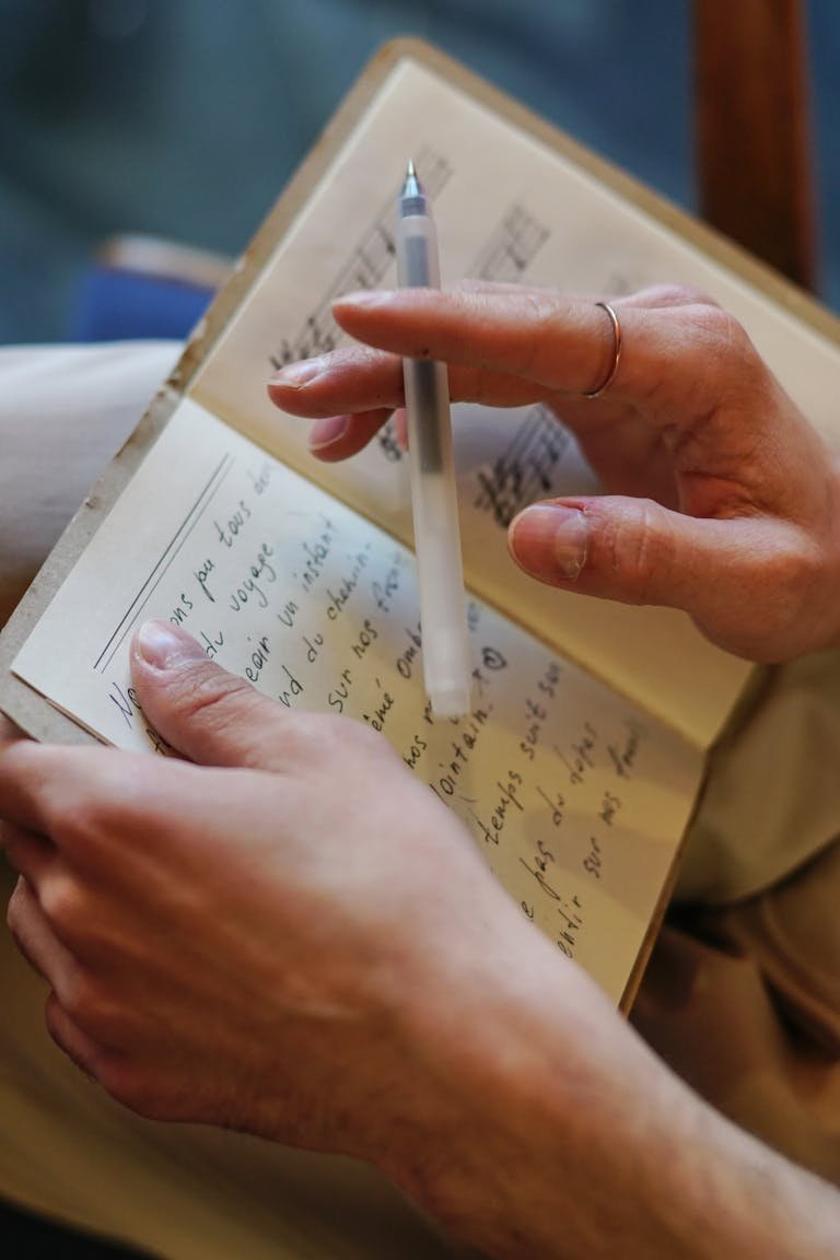 Lyrics Close-up image of a woman writing with a pen in a notebook. Ideal for themes of creativity and songwriting.