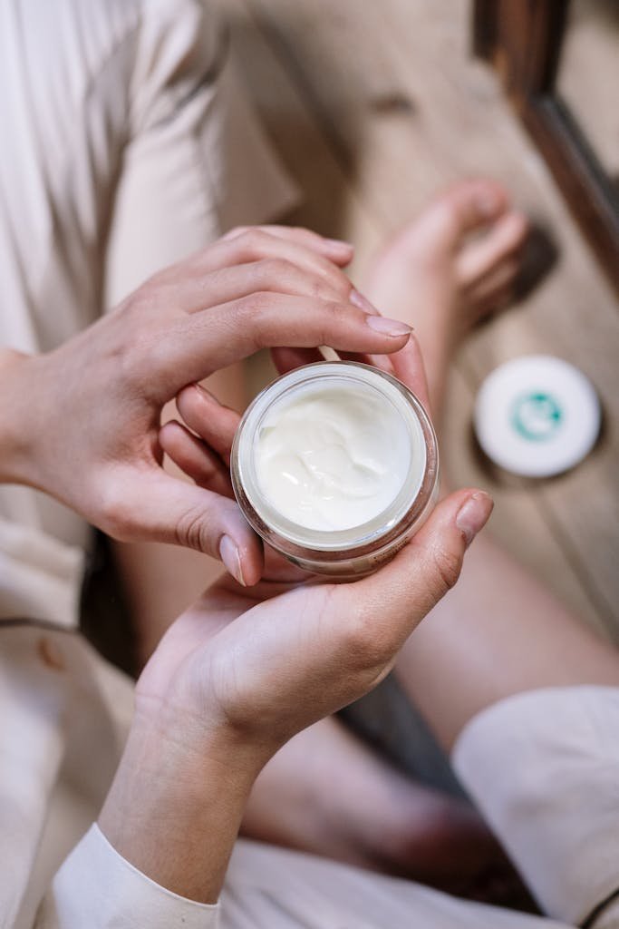 Skin Care in Hindi Wellhealthorganic Close-up of woman's hands applying skincare cream during morning routine indoors.