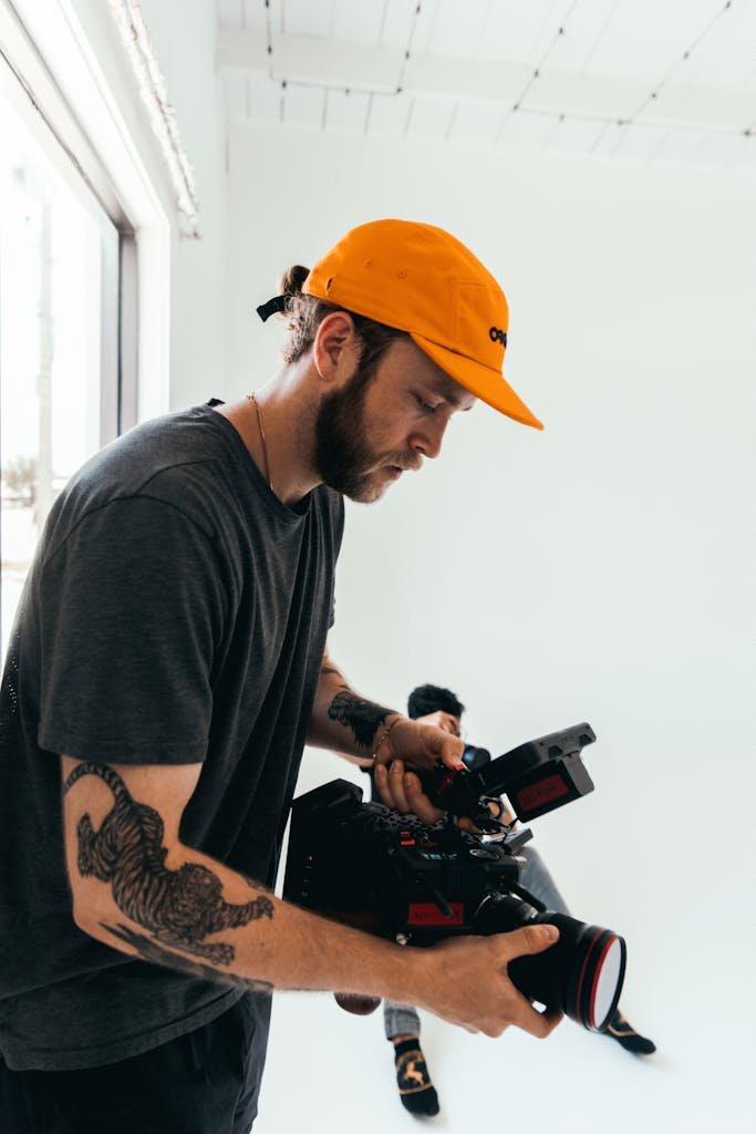 Cinematographer adjusting camera gear on set indoors, creating a behind-the-scenes look into film production.