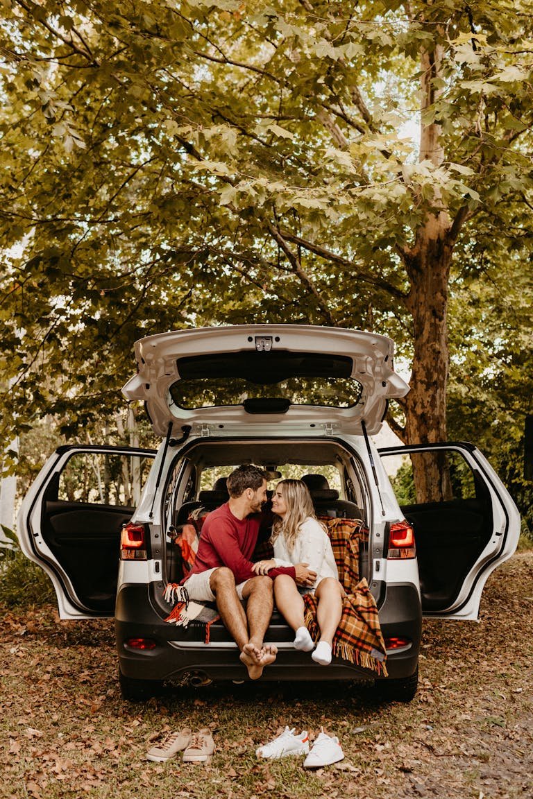 Car Shows Near You This Weekend Couple sitting in the back of a car, sharing a romantic moment outdoors among lush trees.thisvidscat.org